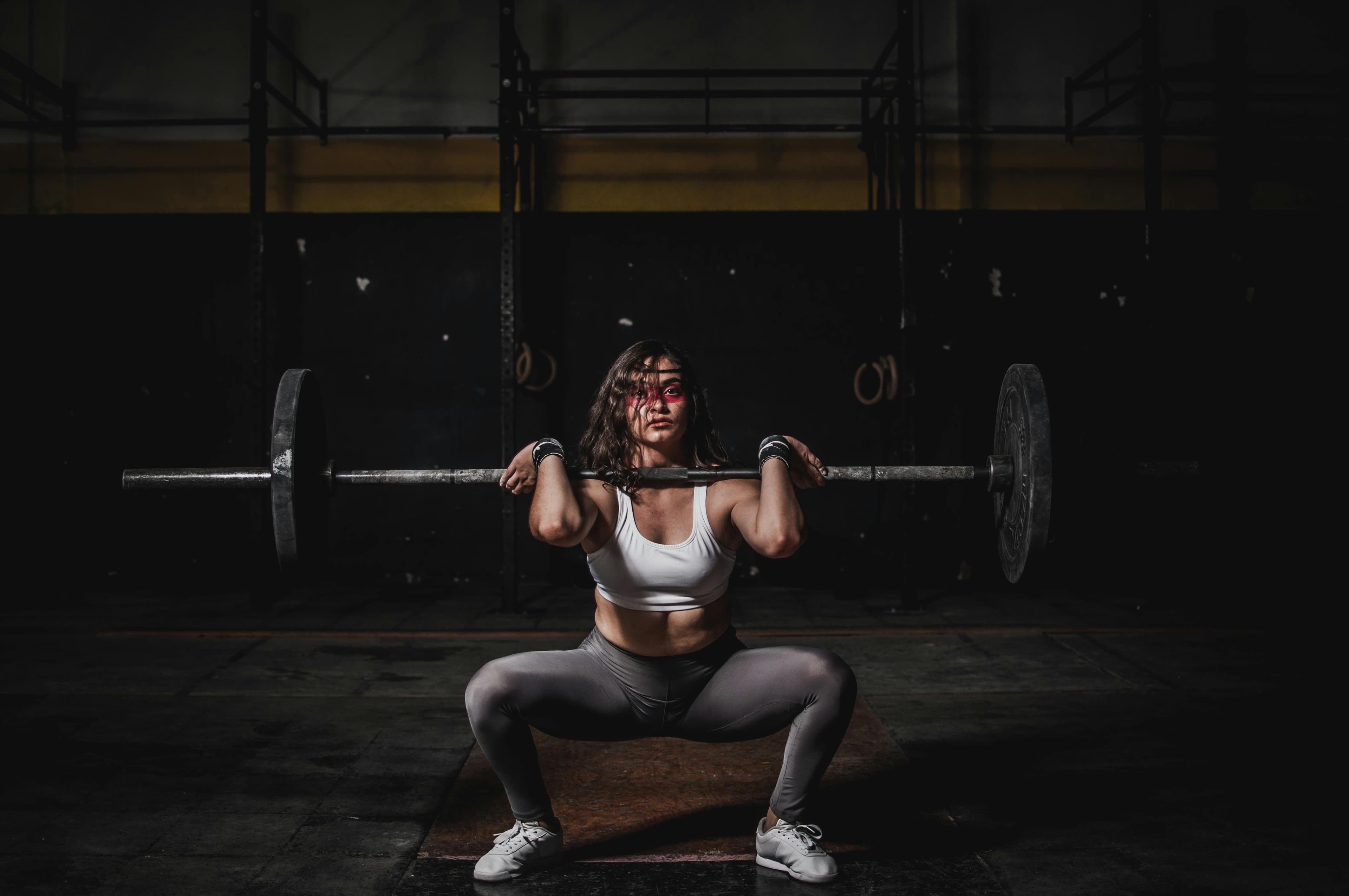 Athlete with barbell, backlit in the gym